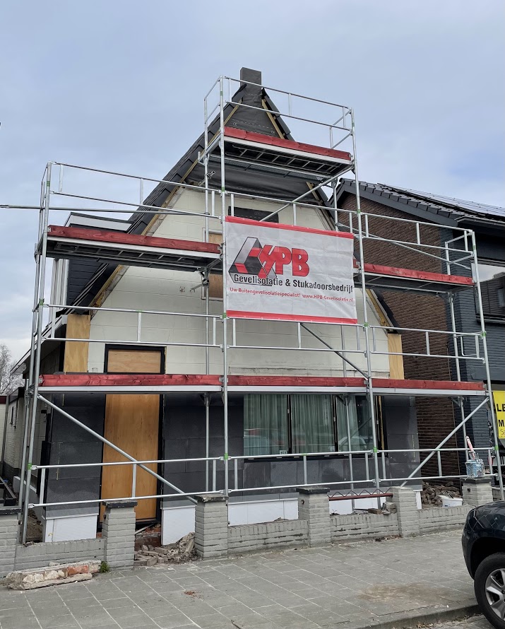 Woning in de steigers met spandoek van HPB Gevelisolatie tijdens het werk aan de gevel